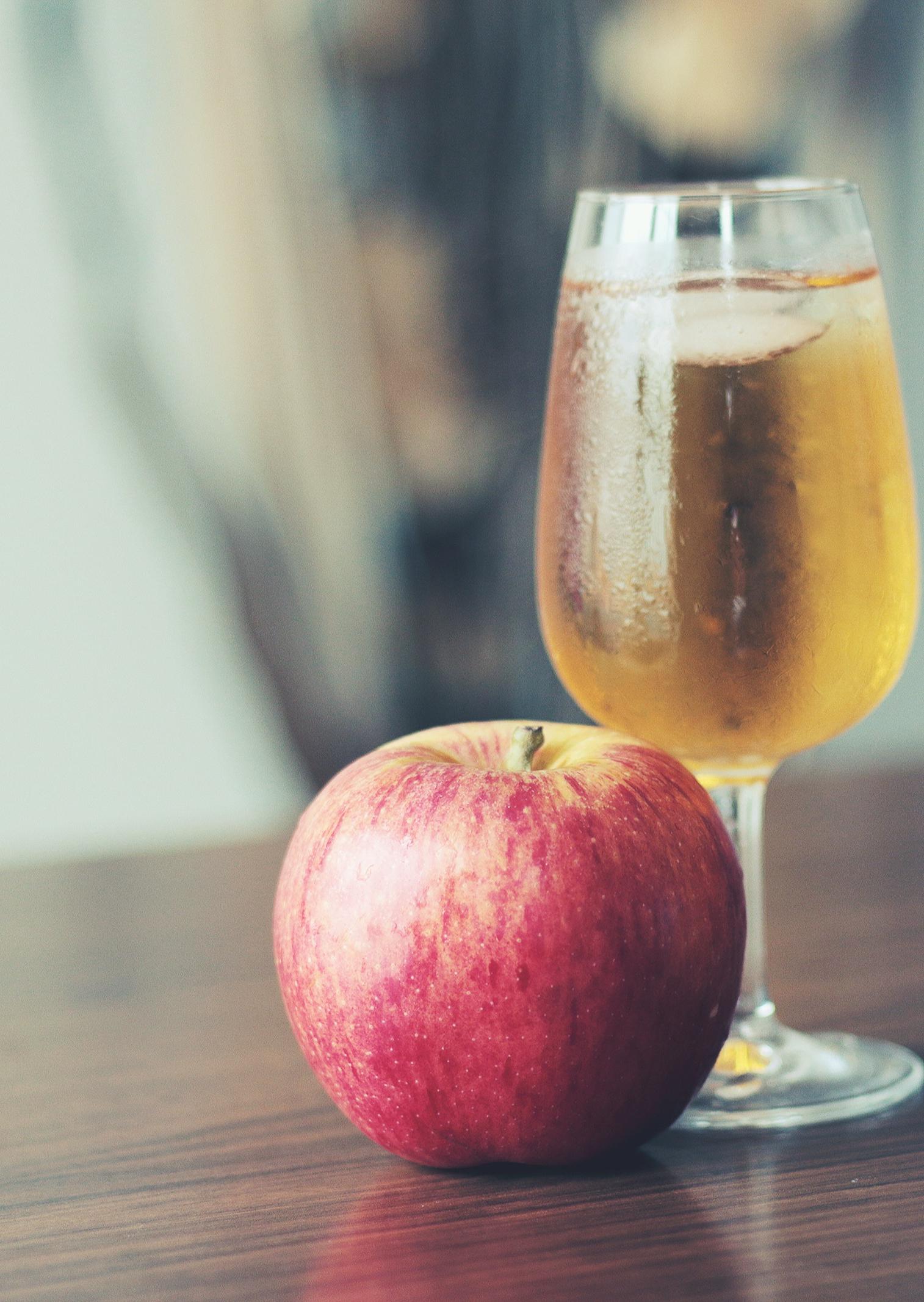 Verre de jus de pomme avec une pomme rouge à côté 