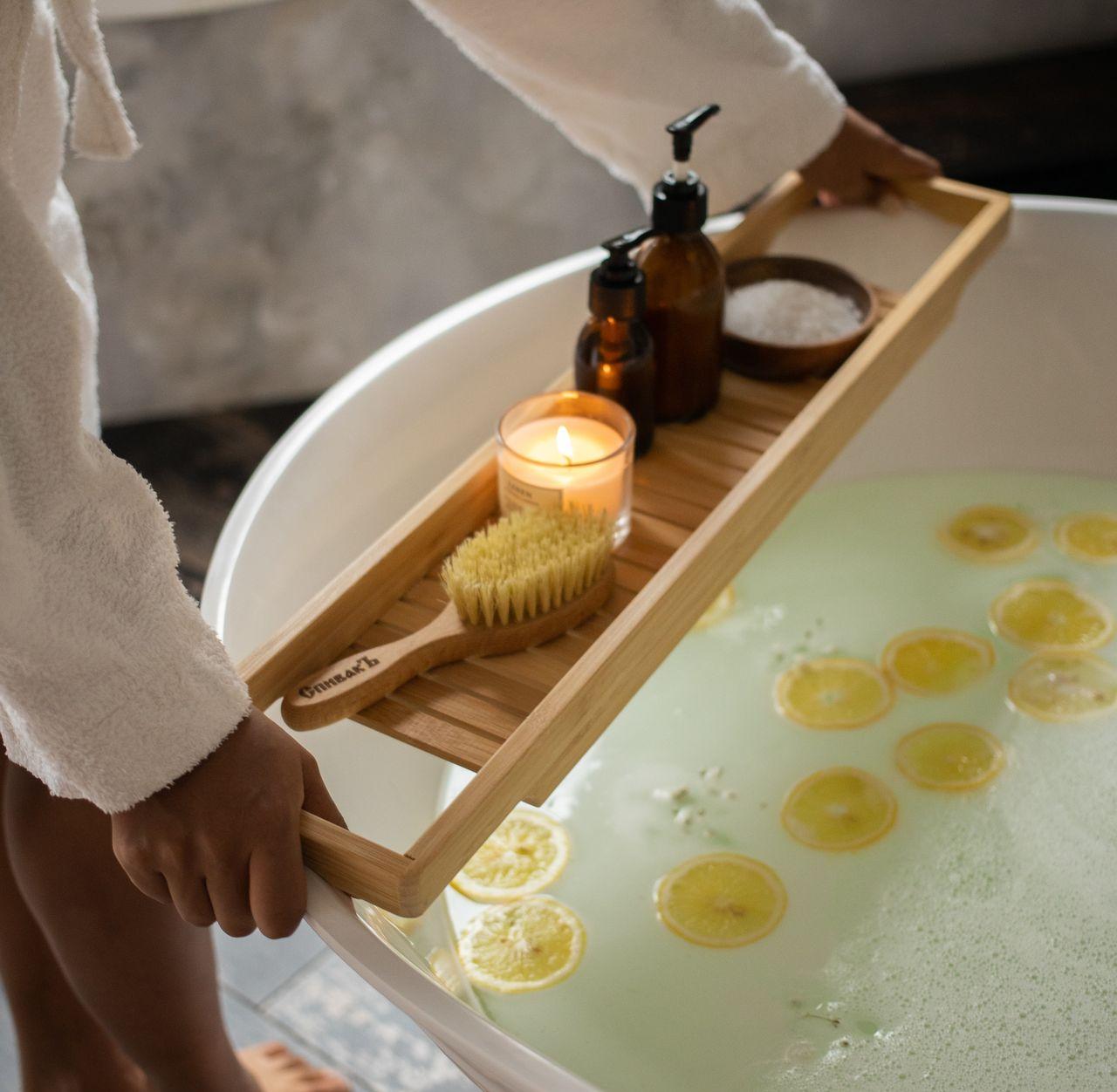 Personne occupée à se préparer un bain cocooning avec des rondelles de citron  